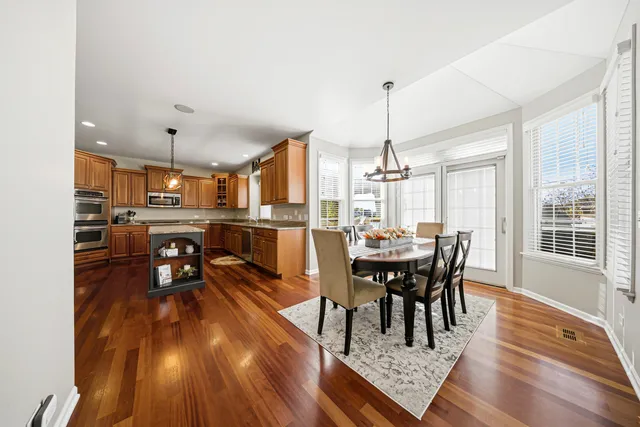 a living room with stainless steel appliances granite countertop furniture wooden floor and a kitchen view