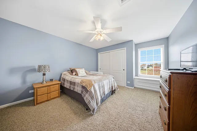 a spacious bedroom with a bed and a flat tv screen on a dresser