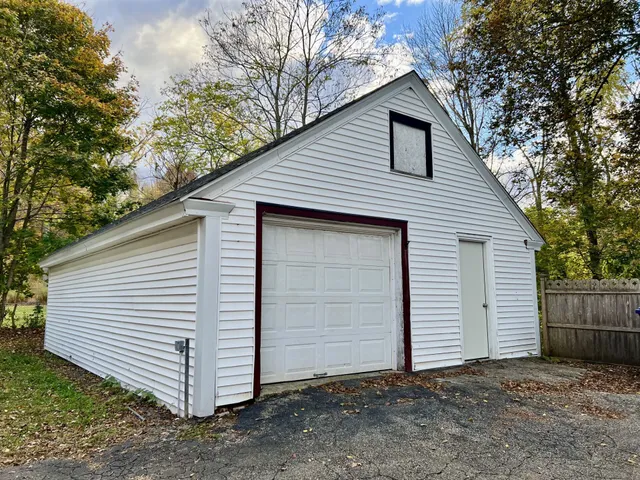 a view of a small white house with a small yard and large tree