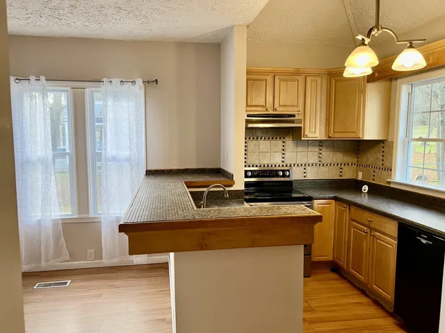 a kitchen with a sink a stove cabinets and a window
