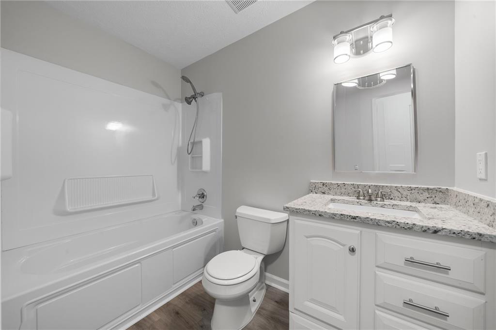 4510 Virginia Avenue Kennesaw, GA 30144 - Photo 34 of 54 a bathroom with a granite countertop sink toilet a mirror and shower