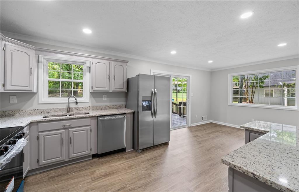 4510 Virginia Avenue Kennesaw, GA 30144 - Photo 9 of 54 a kitchen with stainless steel appliances granite countertop a sink a stove a refrigerator and island with wooden floor