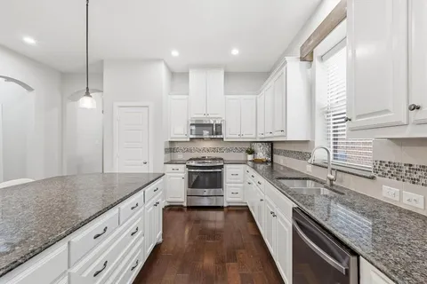 a large kitchen with stainless steel appliances granite countertop a lot of counter space and wooden floors