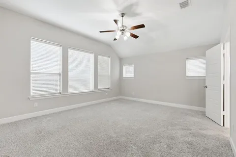a view of an empty room and kitchen with wooden floor