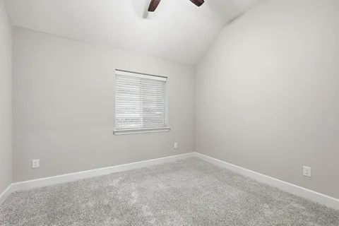 an empty room with a chandelier fan and windows