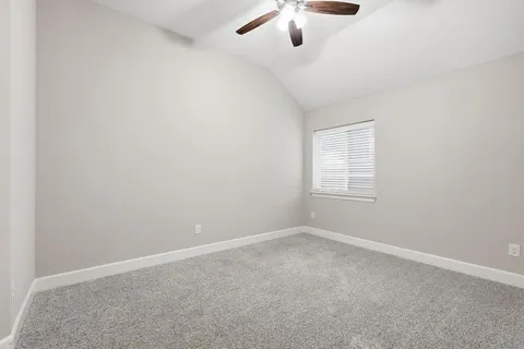 an empty room with a chandelier fan and windows