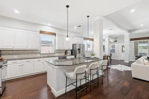 a kitchen with stainless steel appliances granite countertop a kitchen island a hardwood floor and a sink