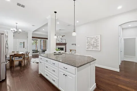 a open kitchen with stainless steel appliances granite countertop a stove a sink a dining table chairs and chandelier