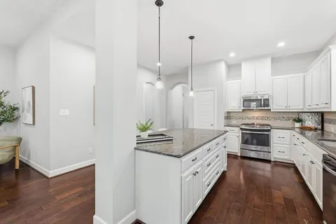 a kitchen with stainless steel appliances kitchen island granite countertop a stove a sink and a wooden floor