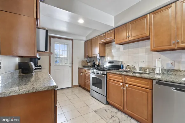 a kitchen with granite countertop stainless steel appliances a sink a stove top oven a counter space and cabinets