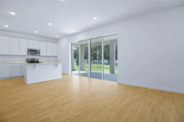 a view of kitchen with stainless steel appliances wooden floor and window
