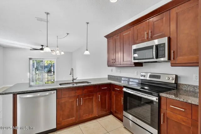 a kitchen with stainless steel appliances granite countertop a sink a refrigerator and a granite counter tops