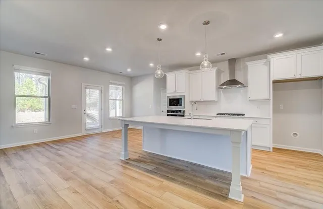 a kitchen with stainless steel appliances granite countertop a stove a sink and white cabinets with wooden floor