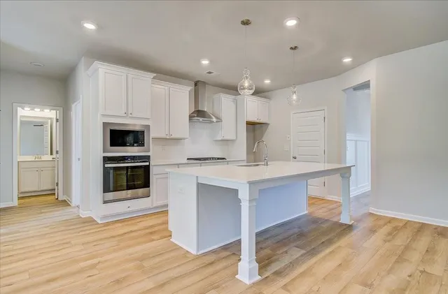 a kitchen with stainless steel appliances kitchen island granite countertop a stove a sink and white cabinets