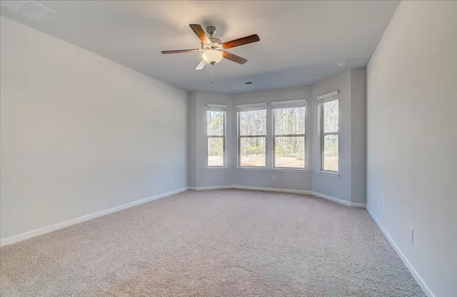 an empty room with ceiling fan and windows