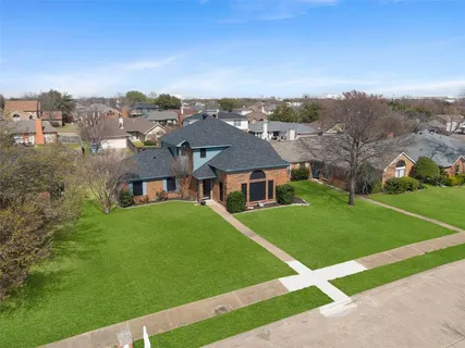 a view of a big house with a big yard and large trees