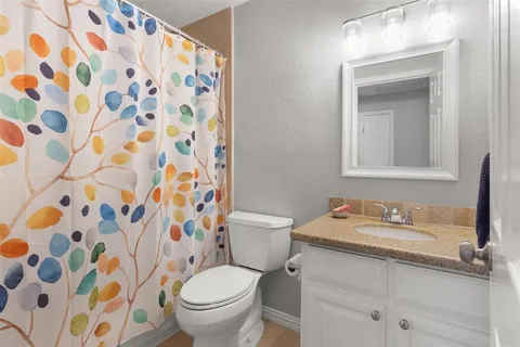 a bathroom with a granite countertop sink a toilet and a mirror