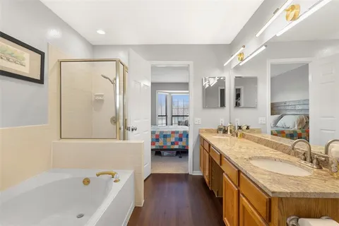 a bathroom with a granite countertop tub double vanity sink and a large mirror