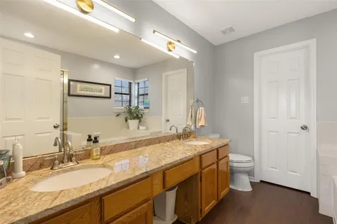 a bathroom with a granite countertop sink a toilet and a mirror