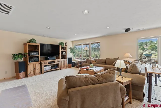 a living room with furniture a flat screen tv and a large window