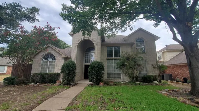 a front view of a house with a garden and plants