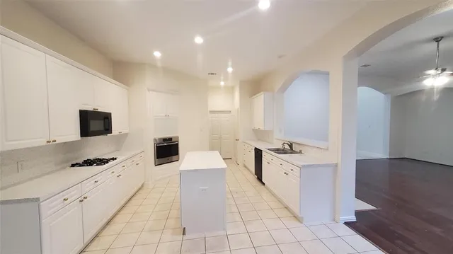 a large kitchen with stainless steel appliances a stove a sink and a refrigerator