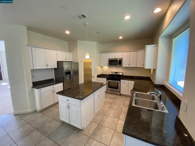 a kitchen with granite countertop a stove sink and refrigerator