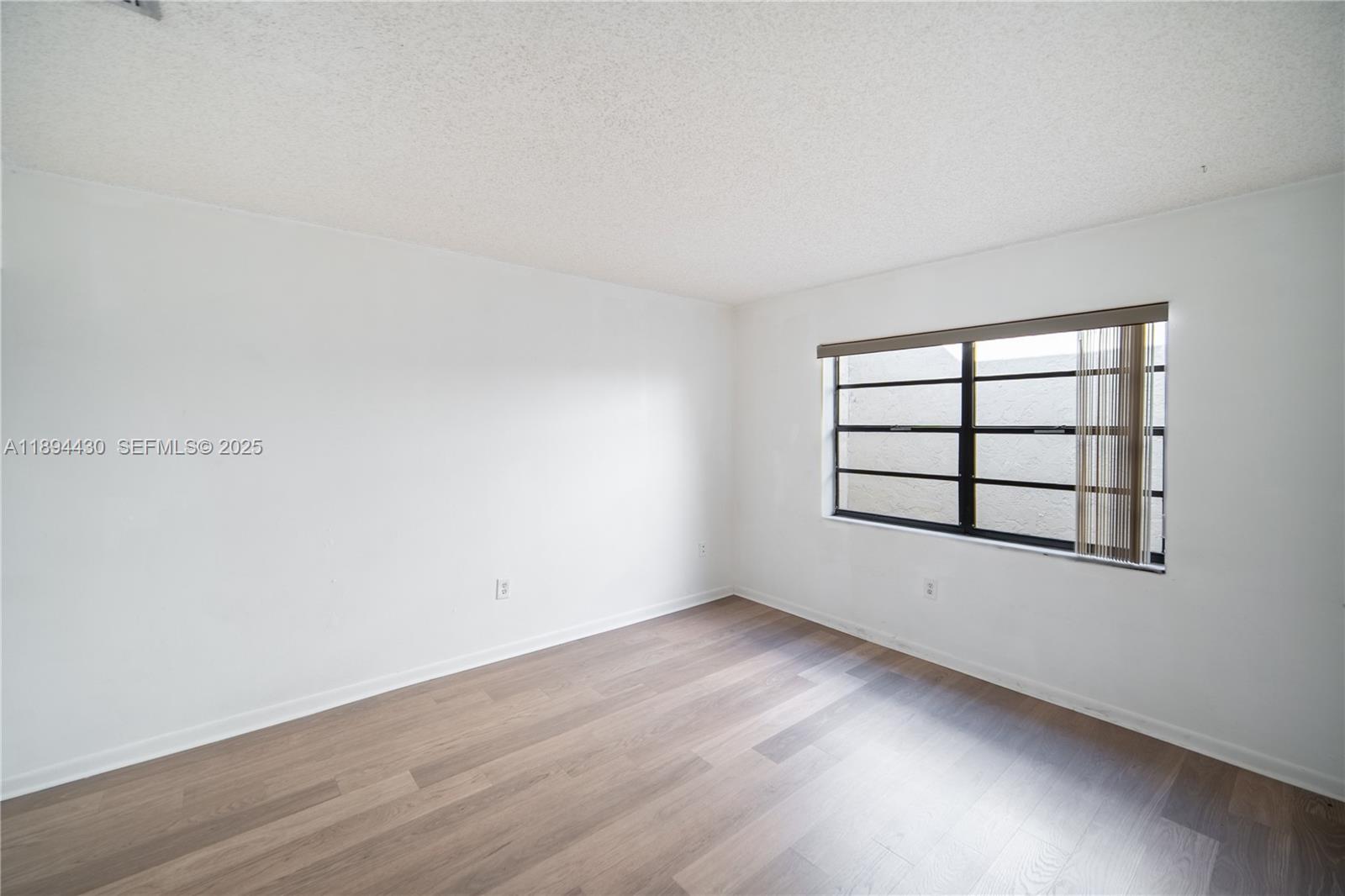 6845 Northwest 169th Street, Unit 41C Hialeah, FL 33015 - Photo 14 of 20 an empty room with wooden floor and windows