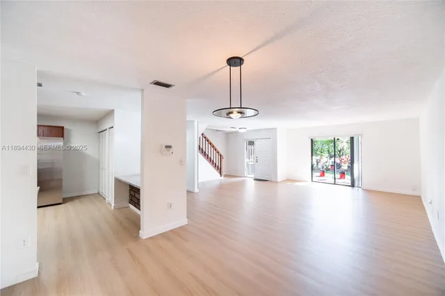 a view of a hallway with wooden floor and a chandelier