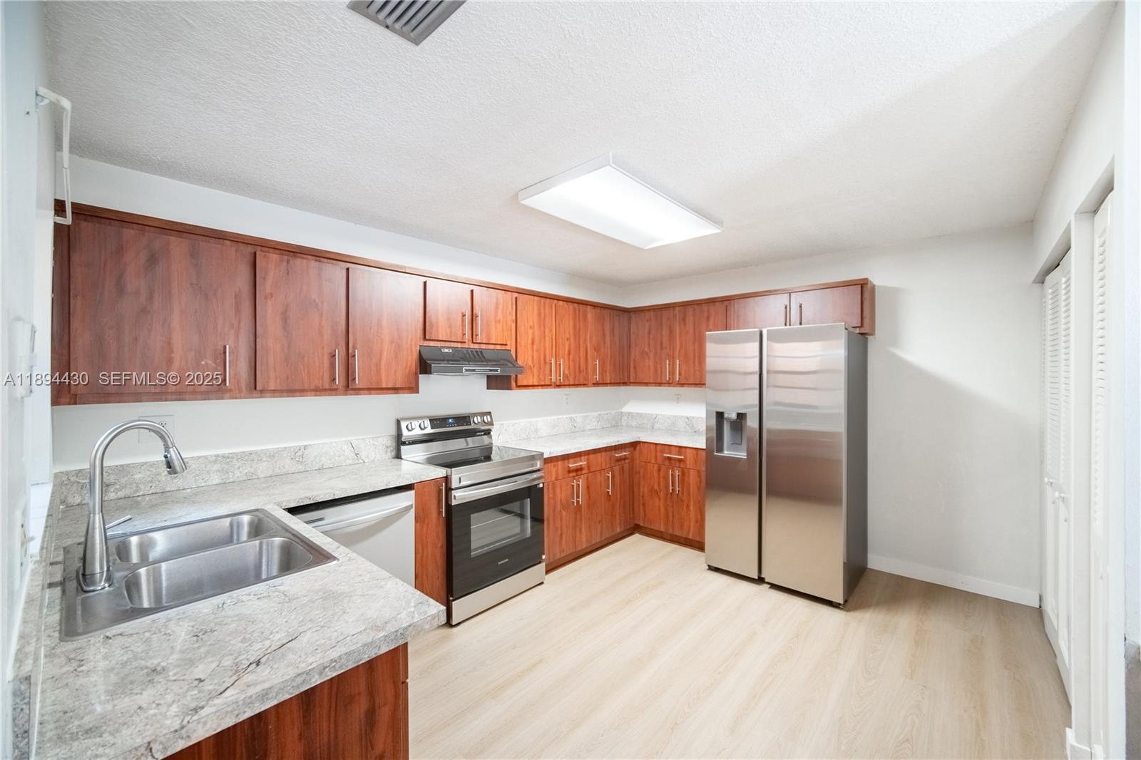 6845 Northwest 169th Street, Unit 41C Hialeah, FL 33015 - Photo 5 of 20 a kitchen with granite countertop a refrigerator a sink a stove and cabinets