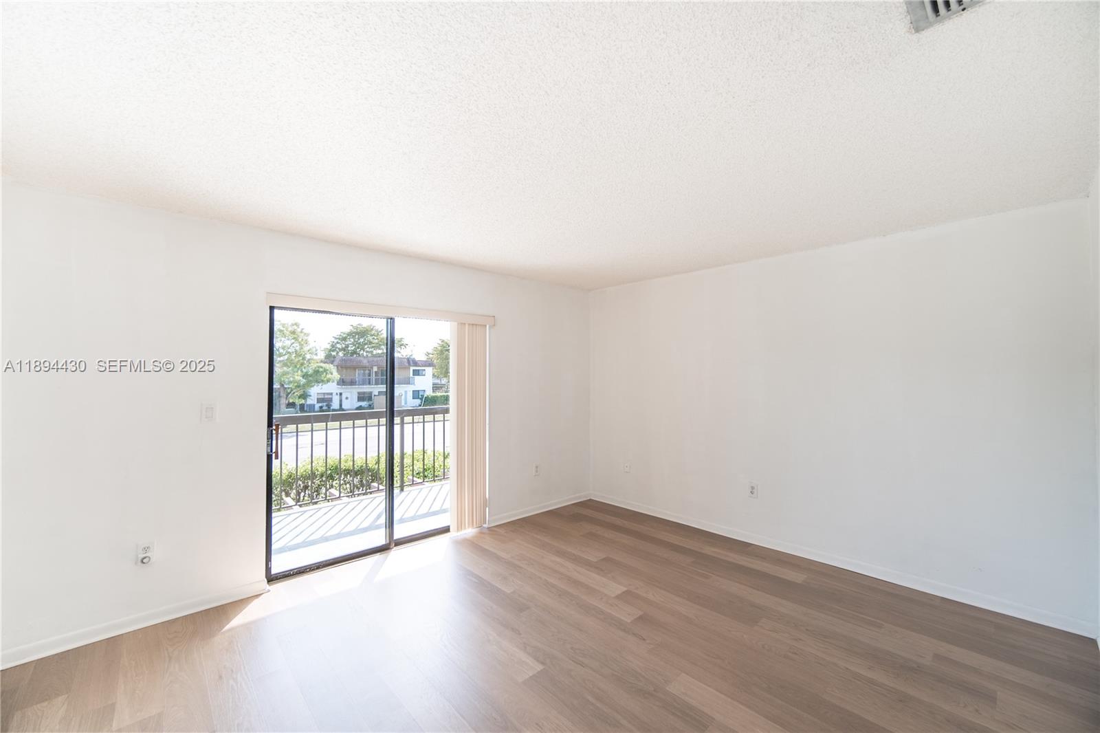 6845 Northwest 169th Street, Unit 41C Hialeah, FL 33015 - Photo 9 of 20 a view of an empty room with wooden floor and a window
