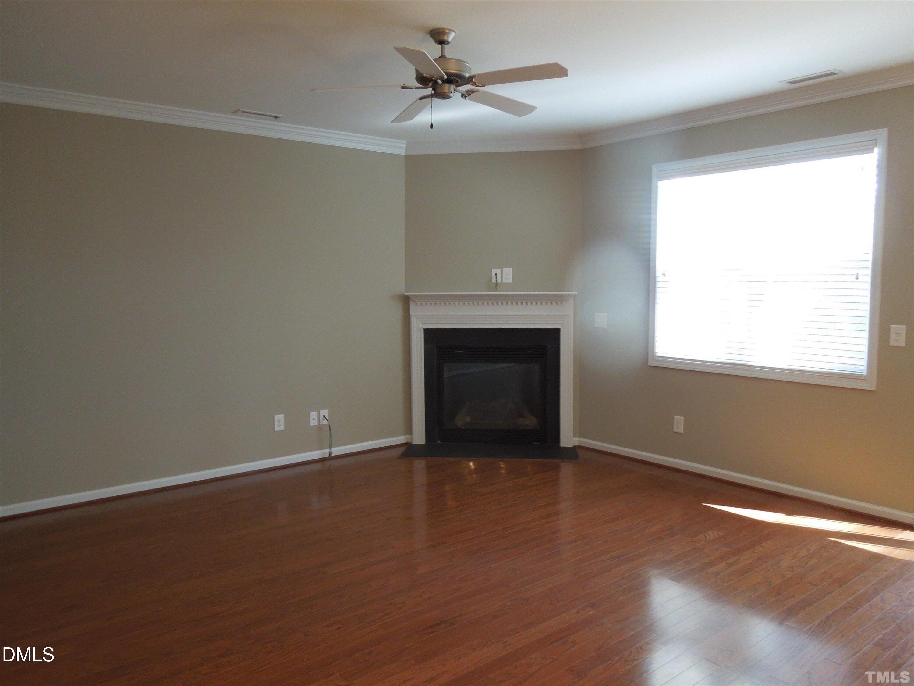 4622 Altha Street Raleigh, NC 27606 - Photo 2 of 8 an empty room with wooden floor fireplace and windows