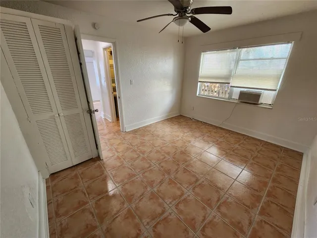 an empty room with windows and fan