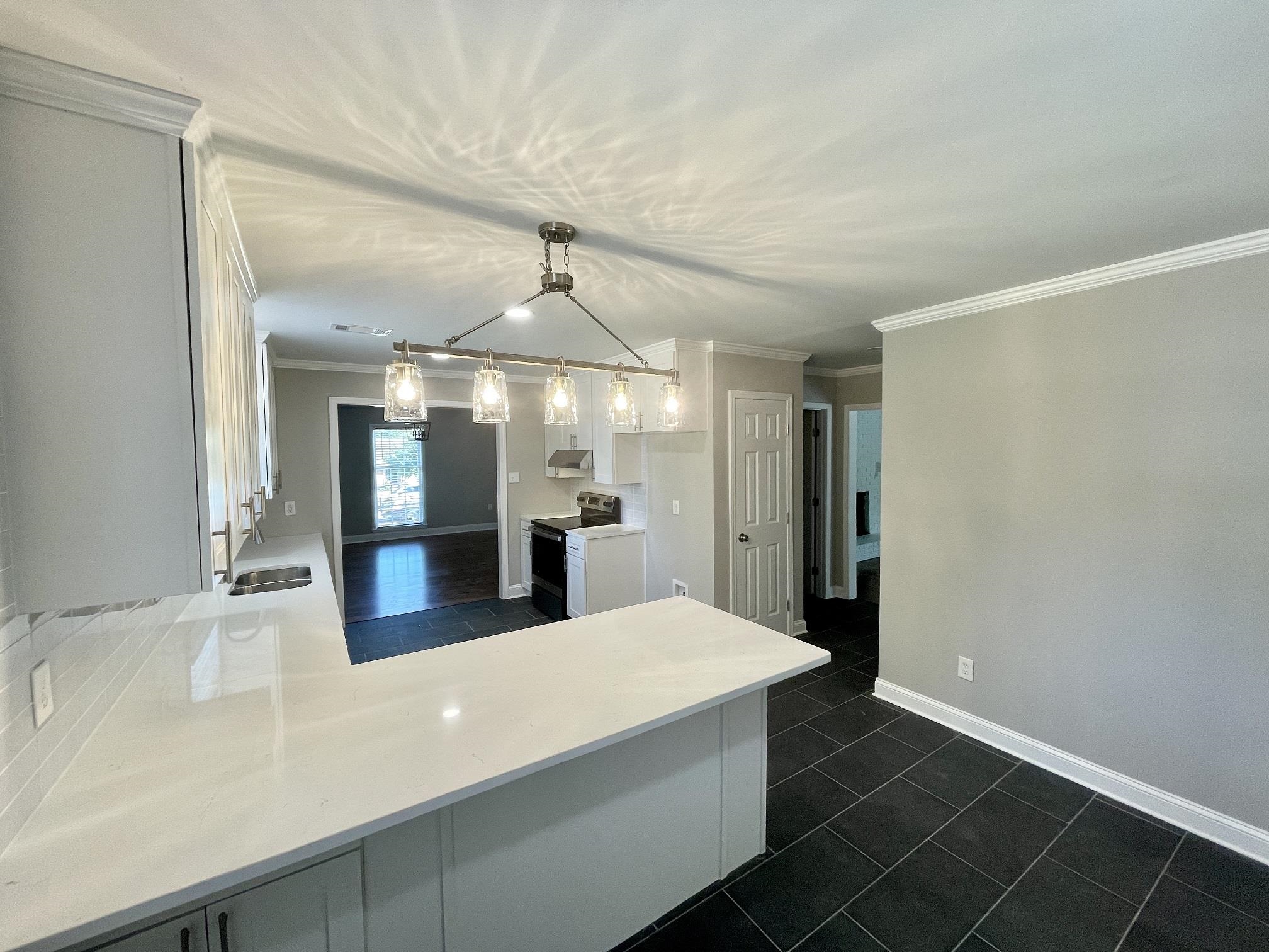 5523 Walnut Grove Road Memphis, TN 38120 - Photo 12 of 21 a view of a kitchen with kitchen island a sink wooden floor and a chandelier
