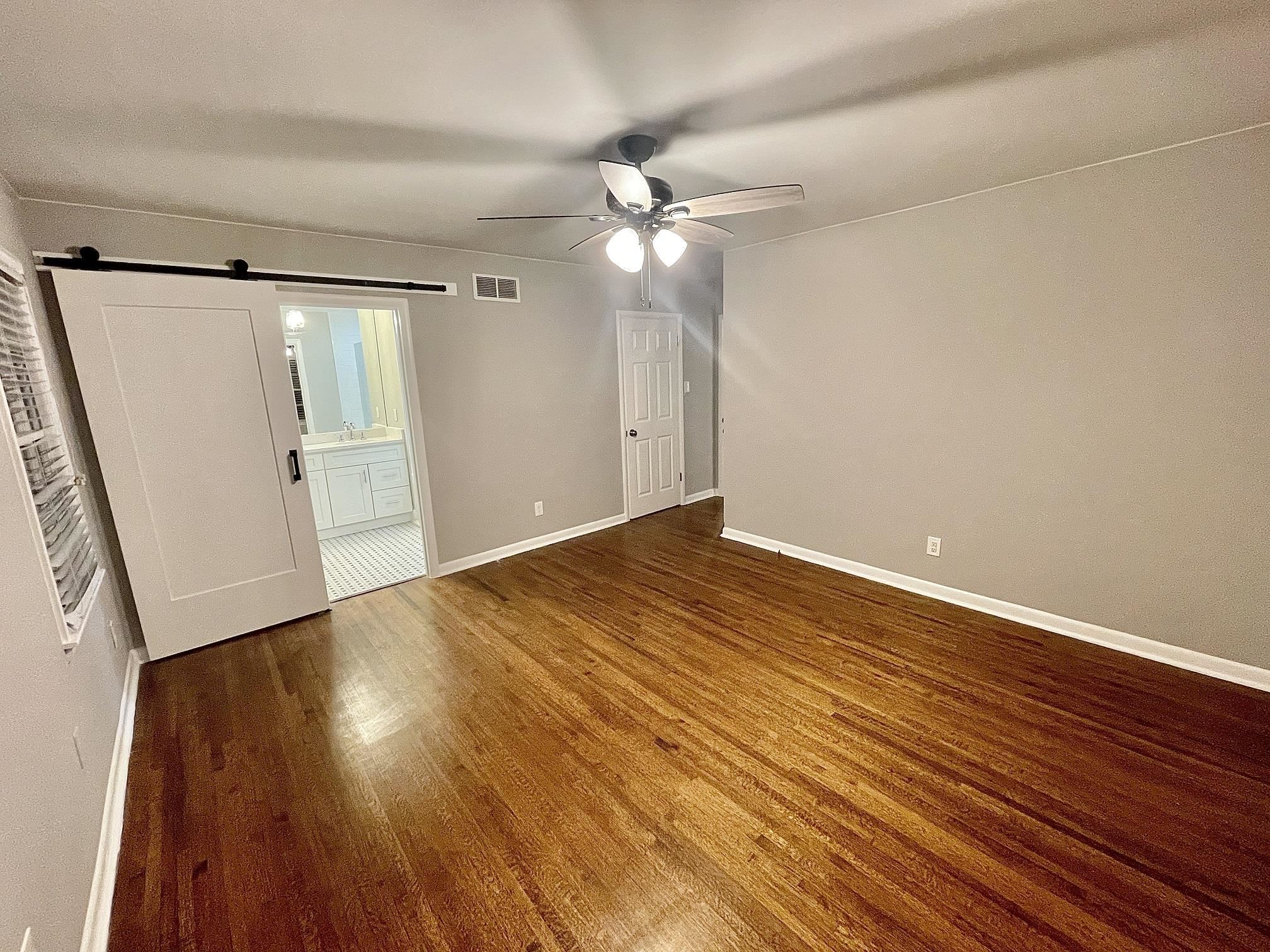 5523 Walnut Grove Road Memphis, TN 38120 - Photo 18 of 21 a view of an empty room with wooden floor and a ceiling fan