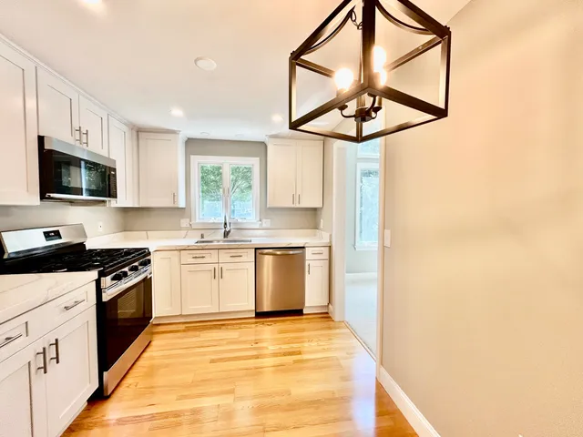 a kitchen with stainless steel appliances granite countertop a sink a stove a refrigerator cabinets and a window