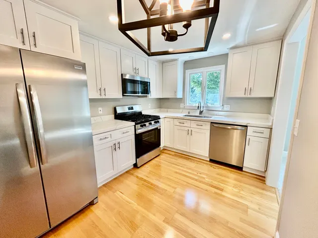 a kitchen with stainless steel appliances granite countertop a refrigerator a stove a sink and white cabinets