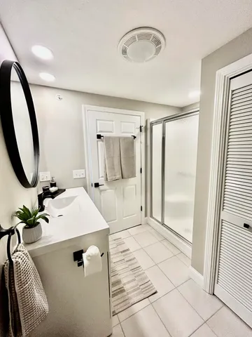 a bathroom with a sink a mirror a potted plant and a shower
