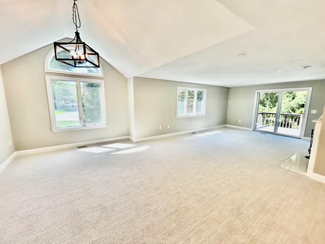 a view of an empty room with window and a kitchen