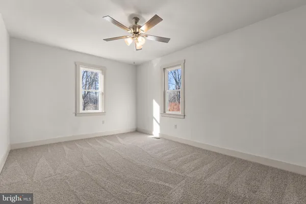 an empty room with windows and fan