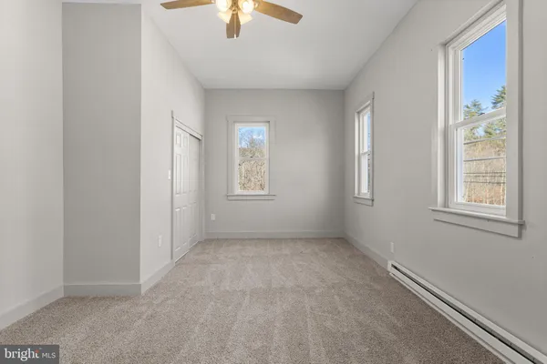 an empty room with windows and chandelier fan