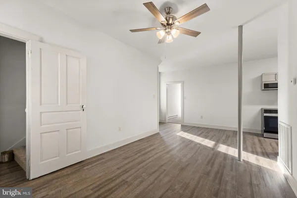 an empty room with wooden floor and ceiling fan