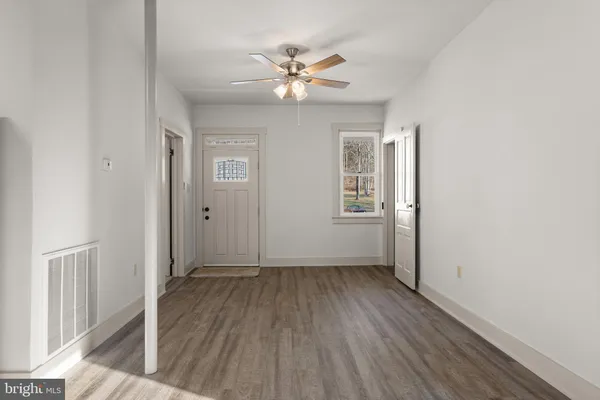 an empty room with wooden floor fan and windows
