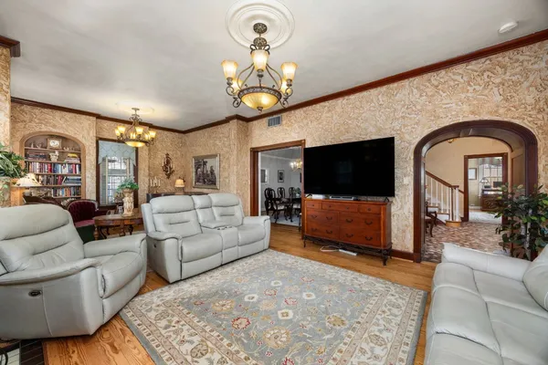 a living room with furniture a flat screen tv and a chandelier