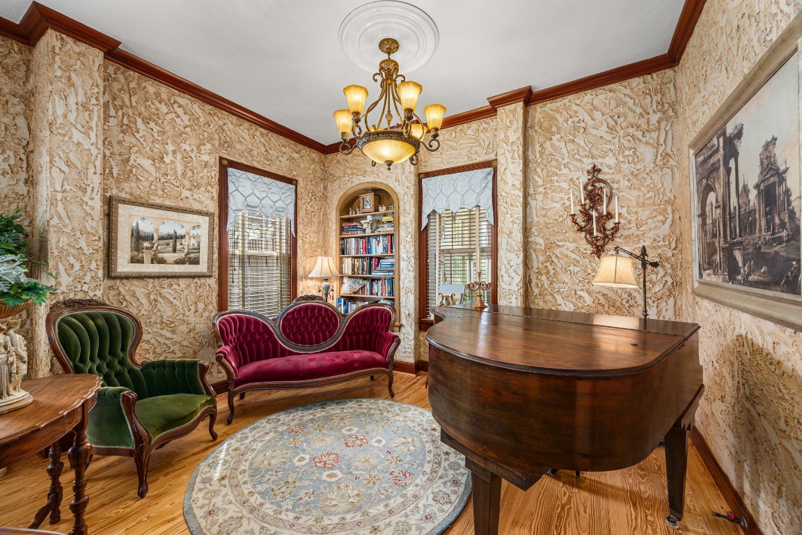 801 West Main Street Brenham, TX 77833 - Photo 13 of 50 Tucked just beyond the formal living room, this charming sitting area offers the perfect space for conversation, reading, or music. An arched built in bookcase, elegant lighting, rich textured walls, and beautiful hardwood floors continue the home's timeless style and historic appeal.