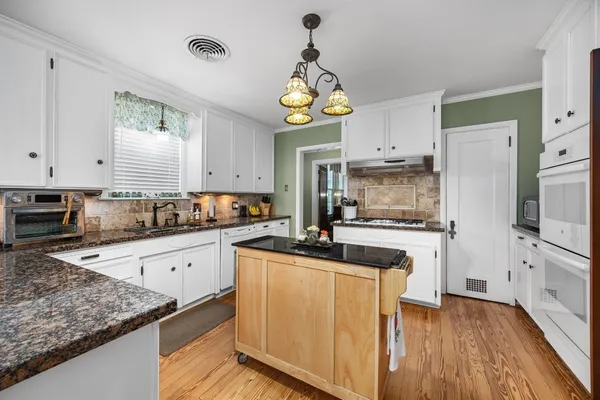 a kitchen with cabinets a center island stainless steel appliances and a window