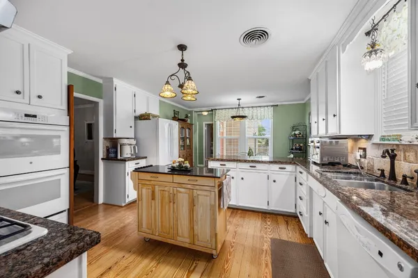 a large kitchen with stainless steel appliances kitchen island granite countertop a stove refrigerator and cabinets
