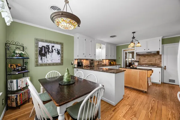 a kitchen with stainless steel appliances granite countertop a dining table chairs stove and a refrigerator