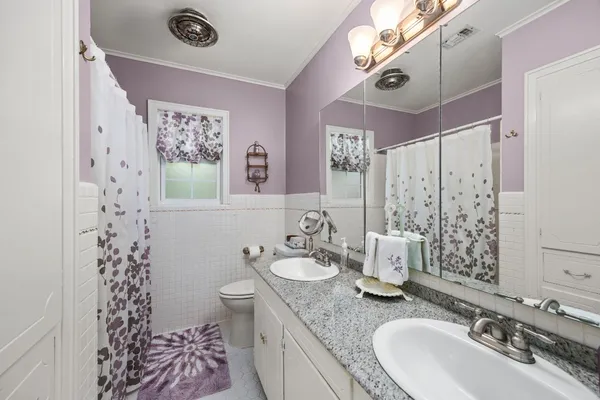 a bathroom with a granite countertop double vanity sink mirror and shower