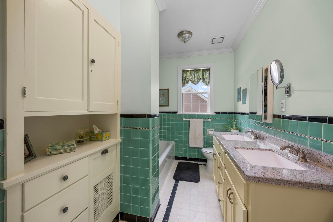 801 West Main Street Brenham, TX 77833 - Photo 29 of 50 The upstairs primary ensuite offers dual sinks, generous counter space, and abundant built in cabinetry for storage. Vintage inspired tilework adds character.